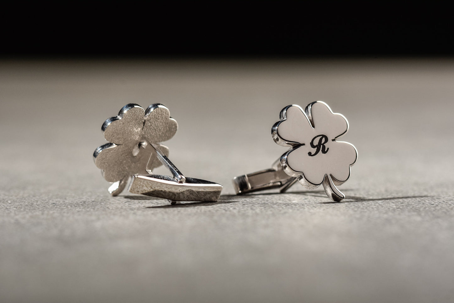 Close up of custom engraved initials on clover shaped silver cufflinks