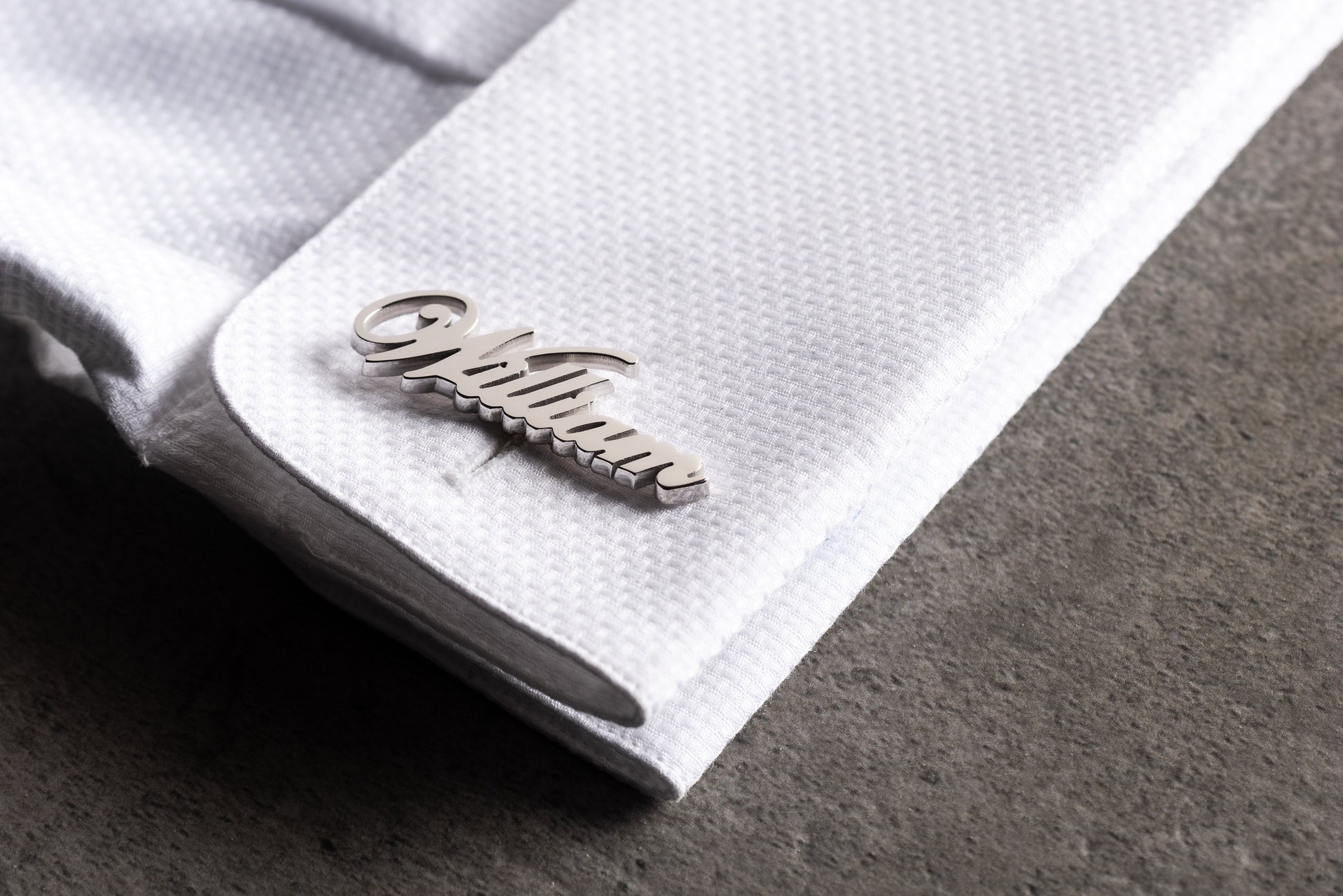Close up of personalized 18k gold plated name cufflinks in script font