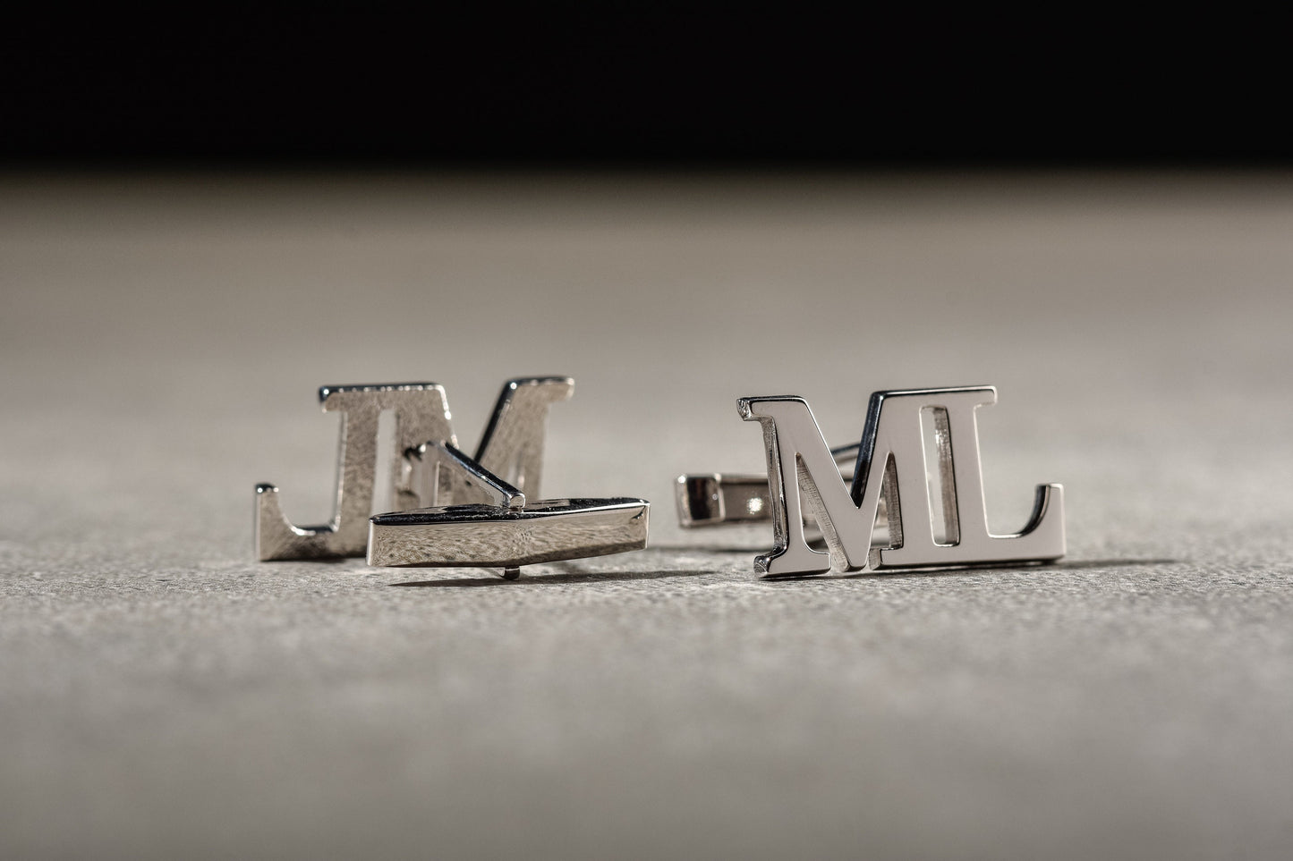 Detailed view of custom engraved initial cufflinks in silver and gold finishes