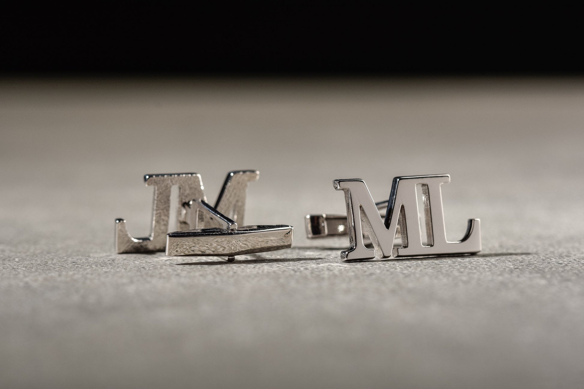Detailed view of custom engraved initial cufflinks in silver and gold finishes